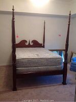 Full view of the queen four poster bed with mattress and boxspring assembled in a bedroom corner.