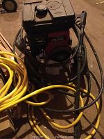 Front angle of the Briggs & Stratton Industrial Plus pressure washer, showing engine and attached hose and wand