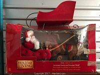 Photo of boxed animated Santa on reindeer pulling red wooden sleigh, labeled Holiday Living, 18 inches tall.