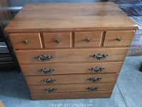 Front view of the wooden chest showing four large drawers with ornate metal handles and a top row of four small drawers with round knobs.