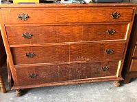 Front view of worn wooden chest of drawers with visible scratches and missing bottom drawer.