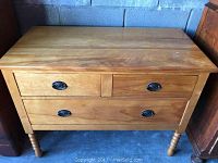 Full front view of the maple low boy dresser showing three drawers and turned legs.