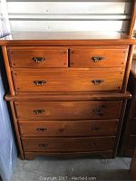 Front view of the wooden chest of drawers with all drawers closed, showing 2 smaller top drawers and 3 larger bottom drawers with metal handles, wood grain, and visible knots.