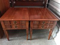 Pair of wooden end tables side by side with fluted drawer fronts and brass ring pulls.