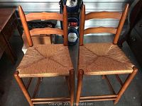 Pair of wooden bar stools with woven seats and curved backs shown from above and front angles.