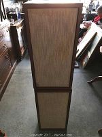 Pair of KLH vintage speakers standing side by side, covered with beige woven speaker cloth on front and wooden cabinet finish visible on edges.