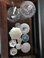 Top-down photo showing crystal cookie jar with lid, crystal ice bucket with silver tongs, Beatrix Potter plate, Lenox candy compote, Ainsley cream and sugar set, Wedgwood ashtray, and coin banks.