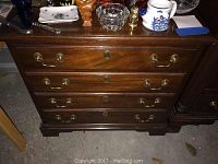 Full front view of Henkel Harris small chest with drawers closed, showing wood grain and brass handles.