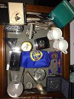 Top-down view of assorted transportation collectibles spread on a glass table including teacups, cutlery, playing cards, medallions, and other memorabilia.