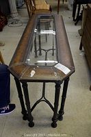 Overall view of the sofa table showing metal legs and glass top with leatherette trim.