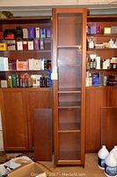 Front view of the tall wooden shelving unit with glass door, showing the full height and wood finish.