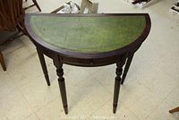 Half-round wooden hall table with green leather-like inlay top and four turned legs.