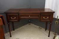 Front view of vanity showing two side drawers, center drawer and carved legs