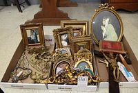 Overview of the lot showing framed pictures, crucifixes, brass decorative items, and old book in a tray
