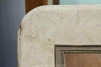 Close-up of paint splatters and corner wear on the white painted table surface.