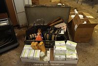 Wide photo showing metal trunk open with vintage tennis rackets and bags inside alongside boxes of oatmeal soap and small figurine
