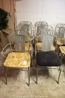Set of six metal framed arm chairs. One with black cushioned seat, one with wooden seat, four with plywood seats.