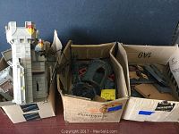Photo of three boxes filled with assorted PlayMobil castle parts including walls and towers.