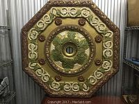 Top down view of large octagonal decorative ceiling medallion with gold, green, and red paint.
