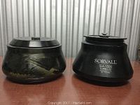 Front side view of two centrifuge rotors, black metal, Sorvall SLA 1500 labeled, both about 11 inches wide and 8 inches tall, show wear.