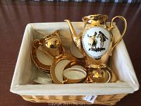Tea set displayed in woven basket including teapot, cream, sugar, plates and cups
