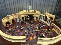 Wide view of the assembly showing arena walls, gladiators, animals, and chariots.