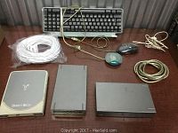 Photo of Apple Pro Mouse, Lacie drives, Smart Disk drive and multiple cables on glass surface