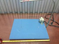Front view of blue hot wire cutter showing wire and base surface with power cord