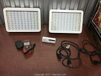 Photo of two rectangular greenhouse LED lamps, Amprobe LED light meter, CO2 meter and power cords on a brown surface