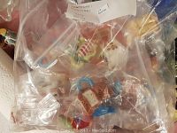 Plastic bag with assorted Red Rose Tea figurines including yellow duck, teapot, and other miniature ceramic pieces