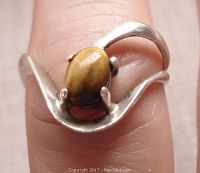 Close-up of the sterling silver open work ring with a tiger eye gemstone on finger showing size and design.