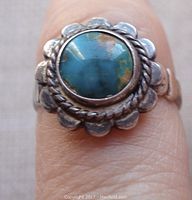 Close-up front view of vintage bell trading post sterling silver ring with green turquoise stone and scalloped bezel setting.