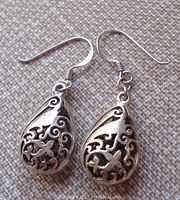 Pair of vintage sterling silver pierced earrings laid flat showing front design and hook wires.