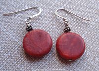 Close up photo showing the round red sponge coral discs on sterling silver ear hooks with small silver bead accents. Each coral disc is around 0.75 inch diameter, earrings are about 1.5 inch total length.