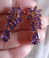 Front view of the pair of earrings showing the gold tone setting with several marquise-shaped purple stones above a teardrop-shaped purple stone.