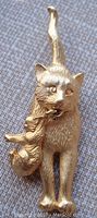 Front angled view of vintage gold tone cat and kitten brooch on fabric background showing detailed texture and face of cats.