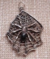 Front view of sterling silver spider pendant showing spider with black stone on web design.