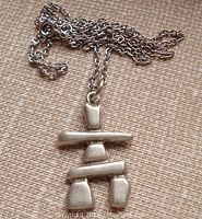 Close-up of the pewter Inuksuk pendant on the chain, showing its stylized shape and chain details.