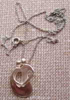 Close-up view of pendant lying on textured fabric background showing mother and child design and chain visible.
