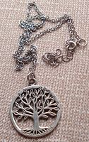 Photo showing the pewter pendant and chain laid out on a textured surface, highlighting the pendant's Tree of Life design and chain clasp.