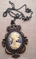 Front view of the cameo pendant and chain showing the carved profile, rhinestones, and detailed crown frame.