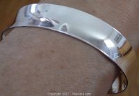 Polished surface and fit on wrist showing concave design and reflective finish.