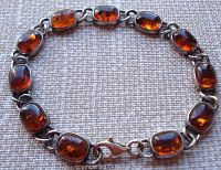 Full view of the amber link bracelet laid out flat showing all amber stones and sterling silver links with lobster claw clasp.