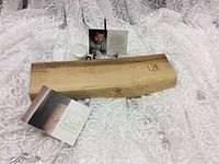 Live edge wooden charcuterie board on white textured fabric with informational cards about the maker.