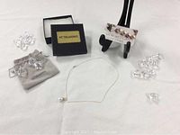 Pendant necklace displayed on table with clear crystal props, box and stand