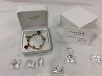 White hinged jewellery box open with bracelet inside, clear acrylic diamonds scattered around, brand card beside.