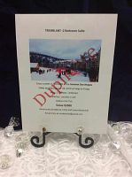 Printed donation certificate in photo stand showing resort image, dates, accommodations, donor and value