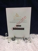 Printed gift certificates for The Ivy Restaurant displayed on a small black stand with decorative clear diamond-like stones placed around. Certificates show logo and value of $100 total.