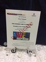 Photo of the gift certificate for two free tickets to the 10 Strings and a Goat Skin concert at Isabel Bader Centre, displayed on a black metal stand with clear decorative crystals around it.