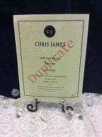 Gift certificate on lace tablecloth with black backdrop, showing CJ logo and printed details
